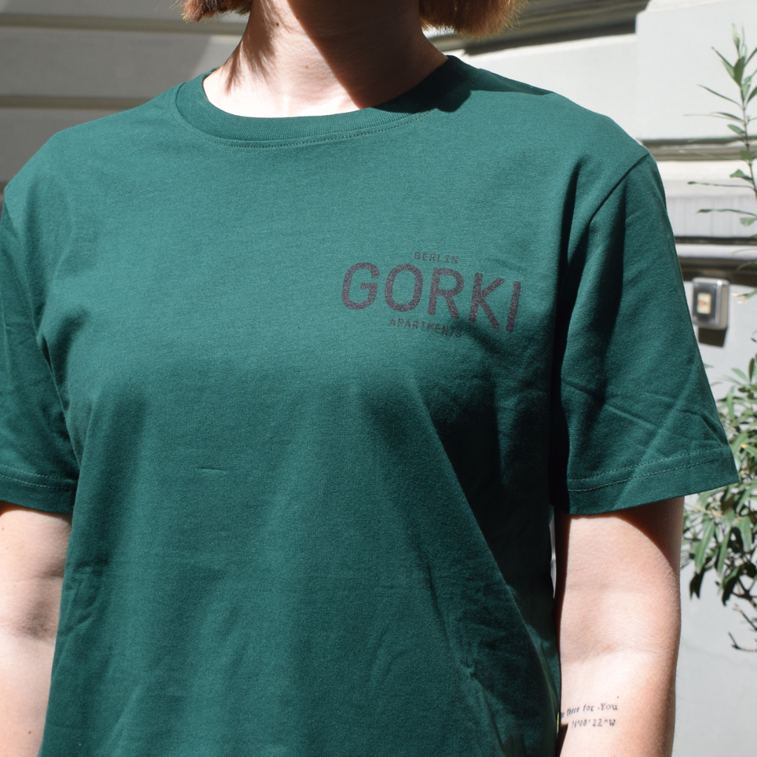 Grünes T-Shirt mit dem GORKI Logo auf der Vorderseite und unsere Fassade auf der Rückseite