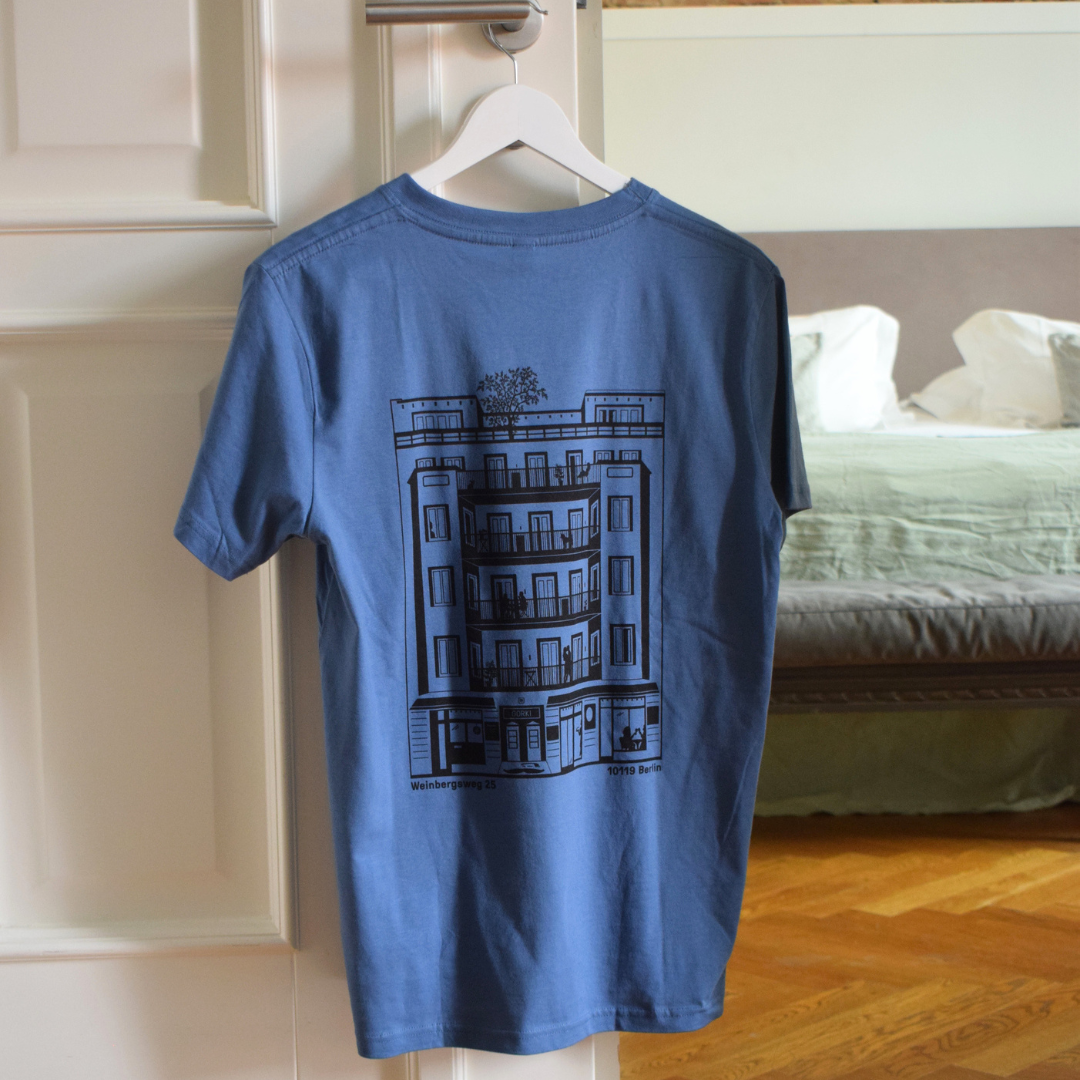 Blaues T-Shirt mit dem GORKI Logo auf der Vorderseite und unsere Fassade auf der Rückseite