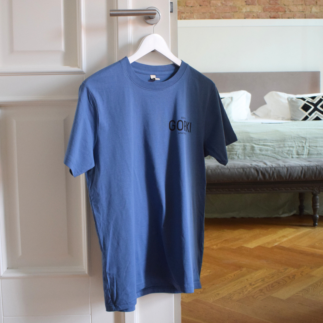 Blaues T-Shirt mit dem GORKI Logo auf der Vorderseite und unsere Fassade auf der Rückseite