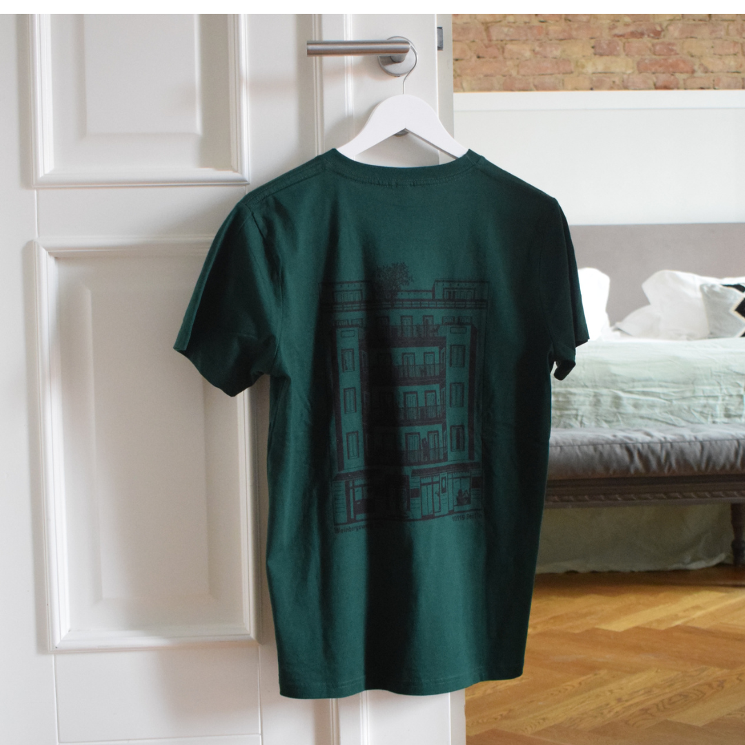 Grünes T-Shirt mit dem GORKI Logo auf der Vorderseite und unsere Fassade auf der Rückseite