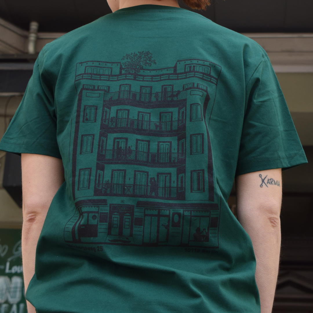 Grünes T-Shirt mit dem GORKI Logo auf der Vorderseite und unsere Fassade auf der Rückseite
